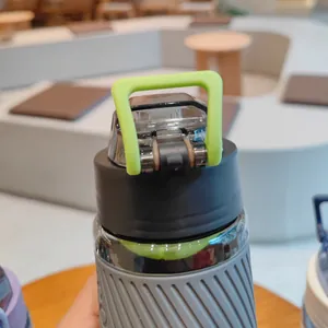 Vue détaillée de la poignée verte fluo sur le bouchon d'une gourde de sport noire.
