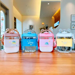 Four cute cartoon square straw water bottles with straps displayed in a warm cafe