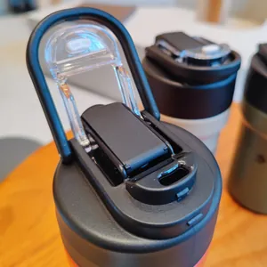 Detail view of a black thermos cup lid featuring a flip-top spout and portable handle
