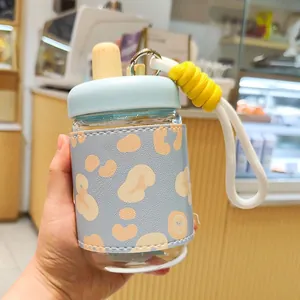 Gourde en verre élégante avec housse léopard et dragonne jaune en gros plan.