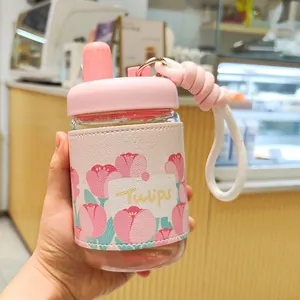 Gros plan d'une bouteille d'eau en verre avec un étui en cuir à motif de tulipes roses