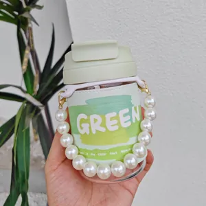 Close-up of portable glass water bottle with large pearl chain and green sleeve