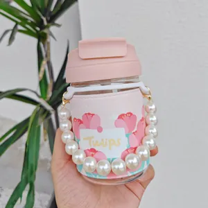 Close-up detail of a pink glass tulip water bottle featuring a decorative pearl handle chain