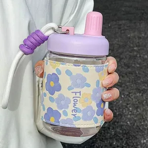 Gourde en verre transparent avec étui en cuir floral et couvercle violet.