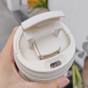 Primo piano del coperchio bianco crema a doppia bevuta di una tazza da caffè in vetro.