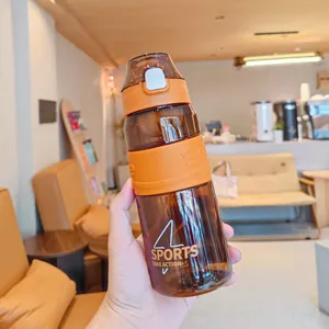 Handgehaltene braun-orange Sport-Wasserflasche mit Klappdeckel in einem Café-Ambiente