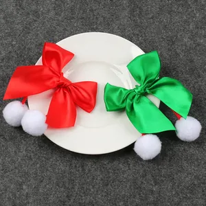 Detalle de lazos festivos de satén rojo y verde con pompones blancos para manualidades.