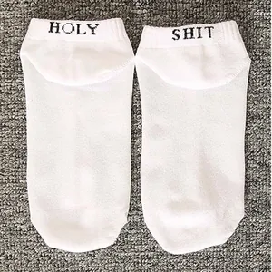 Close-up detail of white cotton boat socks featuring funny HOLY SHIT letters on the heel