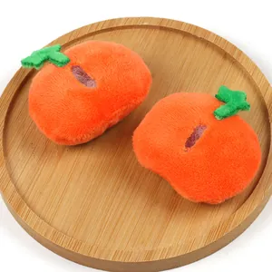 Macro view of two soft orange plush pumpkin accessories displayed on a wooden tray.