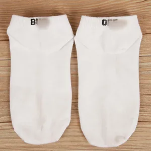 Close-up of white men's boat socks featuring trendy letter prints on the ankle