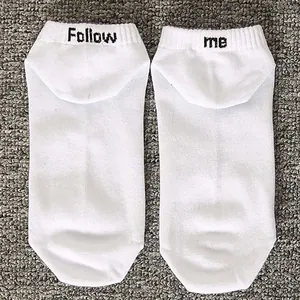 Detailed view of white cotton boat socks featuring 'Follow me' black letter embroidery.