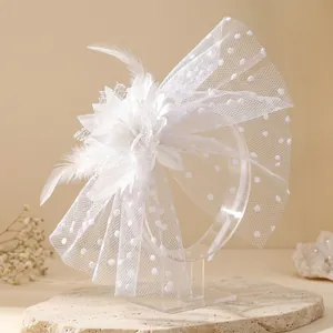 Elegant white bridal fascinator with mesh polka dots and feathers on clear stand