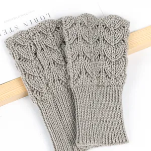 Close-up of grey knitted fingerless gloves with elegant hollow heart pattern texture.