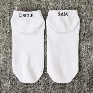 Detail view of white men's ankle socks featuring 'Uncle Sam' black embroidery