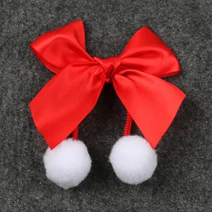 Primer plano de un lazo de satén rojo con pompones blancos para accesorios de Navidad