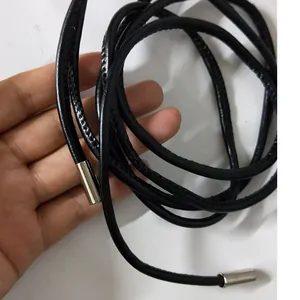 Close-up detail showing the texture of a black thin cord belt with silver metal tips