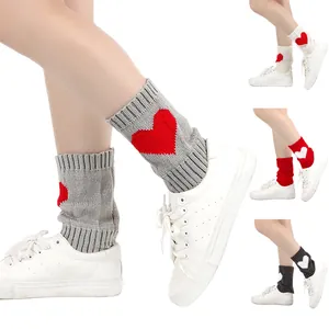 Detailweergave van gebreide beenwarmers met een rood hartpatroon en geribbelde boorden