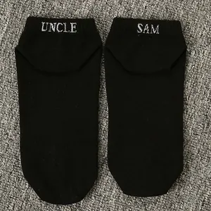 Close-up detail of black ankle socks featuring white Uncle Sam embroidered text design