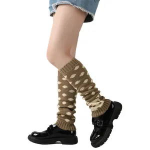Detailopname van bruine gebreide beenwarmers met witte stippen gedragen met zwarte schoenen