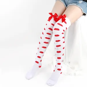 Detail of white over-the-knee socks featuring red lip prints and satin ribbon bows.