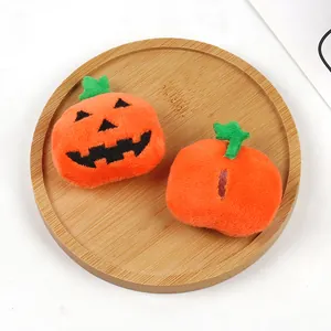 Detailed view of two orange Halloween pumpkin plush charms on a wooden tray