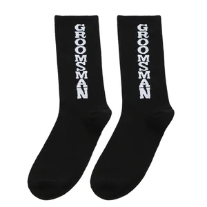 Detailaufnahme schwarzer Socken mit weißem GROOMSMAN-Schriftzug für Hochzeitsfeiern