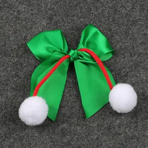 Detalle de lazo de Navidad de satén verde con cordón rojo y pompones blancos suaves