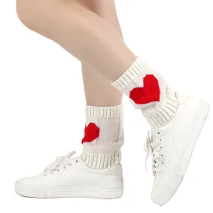 Close-up van witte gebreide beenwarmers met een prachtig en opvallend rood hartjespatroon