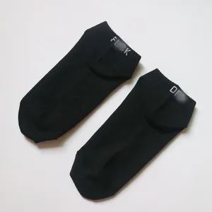 Close-up view of black cotton ankle socks featuring white 'FUCK OFF' embroidered text design