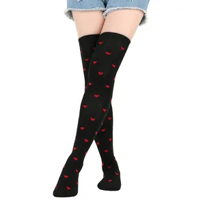 Close-up of black thigh-high socks featuring a red heart pattern for Valentine's Day