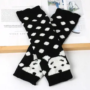 Detailweergave van zwart-wit gestippelde gebreide beenwarmers met schattig puppy-ontwerp