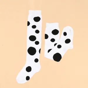 Detailed view of children's white knee-high socks featuring large black polka dots.