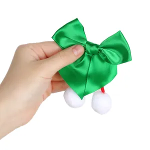 Detalle de un lazo de satén verde con pompones blancos suaves para manualidades de Navidad