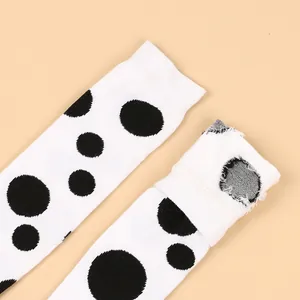 Close-up of white children's high socks featuring a classic black polka dot pattern