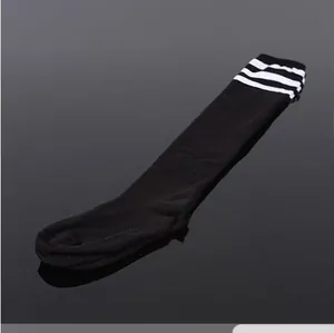 Détail de chaussettes hautes noires avec trois bandes blanches et une texture tricotée.