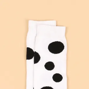 Close-up view of white children's socks with bold black polka dots and ribbed cuffs