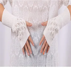 Close-up of white hollow knitted fingerless gloves showing intricate leaf pattern detail.