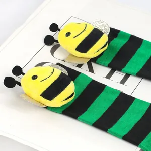 Detail showing plush bee character attached to green and black striped children socks.