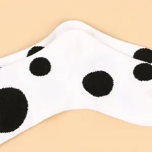 Detailed macro shot of white cotton socks featuring a classic large black polka dot pattern