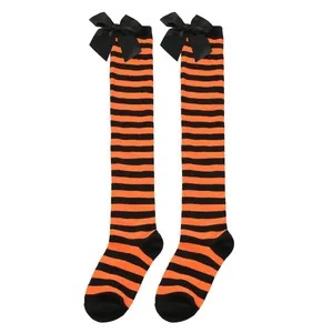 Detalle de calcetines altos a rayas naranjas y negras con elegantes lazos de satén negro