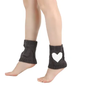 Detailopname van donkergrijze gebreide beenwarmers met wit hartpatroon op de enkels