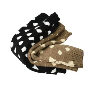 Detail van grof gebreide beenwarmers met een schattig dalmatiër stippenpatroon