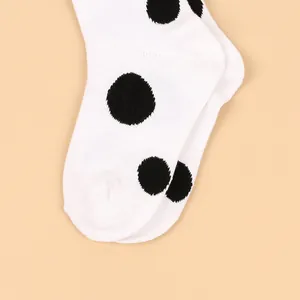 Detail view of white children's knee-high socks with classic large black polka dots