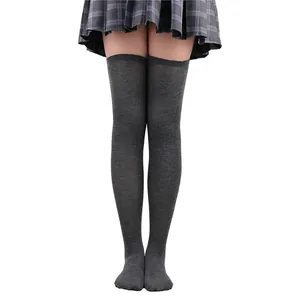 Gros plan de chaussettes hautes tricotées gris anthracite avec une jupe écossaise