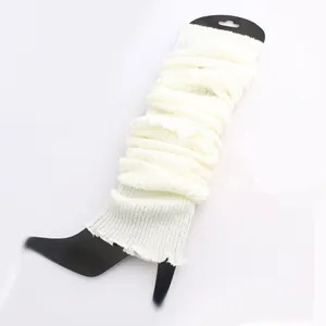 Detailed macro view of white knitted leg warmers displayed on a black leg board