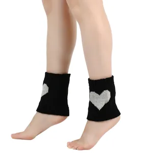 Detailweergave van zwarte gebreide beenwarmers met een contrasterend wit hartmotief