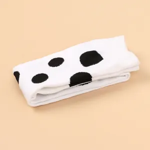 Detail of white children's over-the-knee socks with bold black polka dot pattern