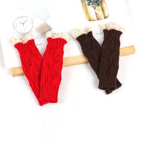 Detailed close-up of red and brown knitted arm warmers with leaf pattern and lace trim accents