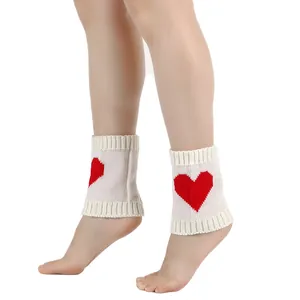 Witte gebreide beenwarmers met rood hartpatroon getoond op benen voor warmte.