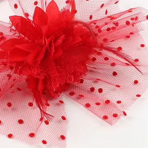 Detailed macro view of a vintage red floral fascinator with feathers and polka dot mesh veil